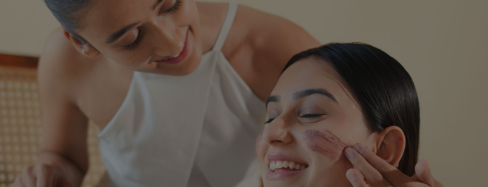Two women applying facial masks, smiling in banner image on padma home page
